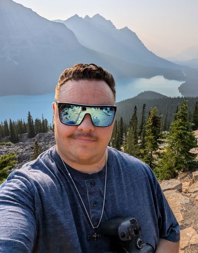 Owen Rempel wearing sunglasses in front of a mountain lake